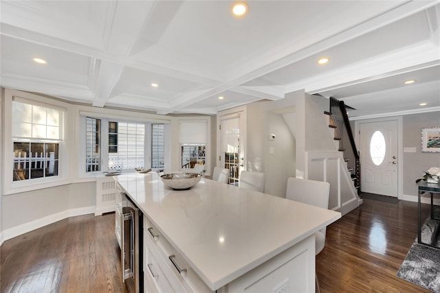 kitchen featuring coffered ceiling, a center island, wine cooler, white cabinets, and beamed ceiling