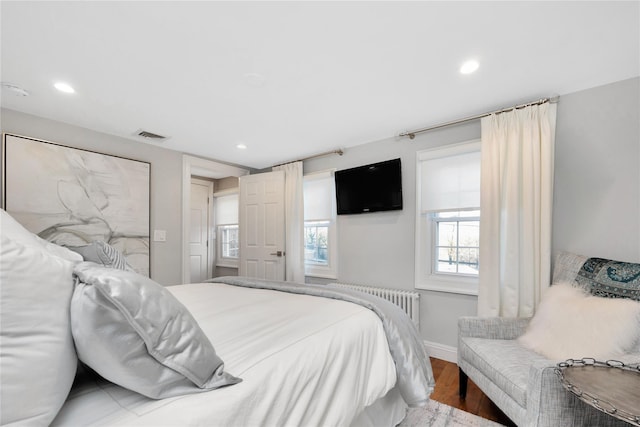 bedroom with radiator heating unit and light wood-type flooring