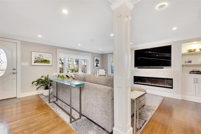 living room with a premium fireplace, crown molding, hardwood / wood-style flooring, and built in shelves