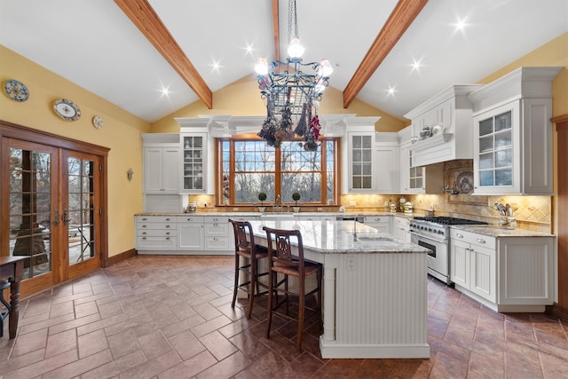 kitchen with decorative light fixtures, white cabinetry, decorative backsplash, a kitchen island, and stainless steel range