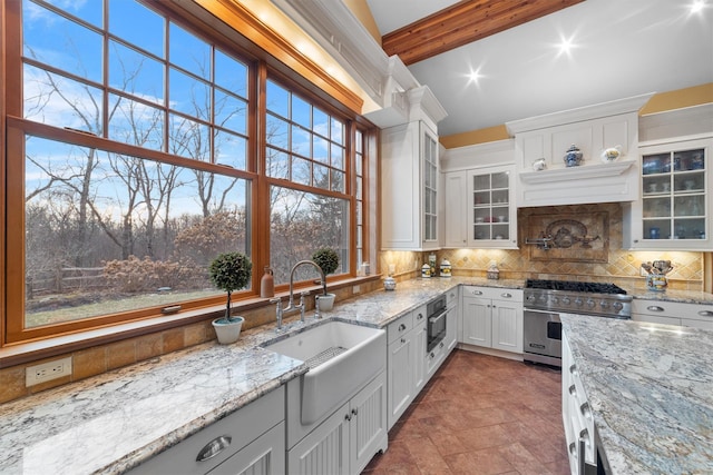 kitchen featuring appliances with stainless steel finishes, white cabinets, light stone countertops, and beamed ceiling