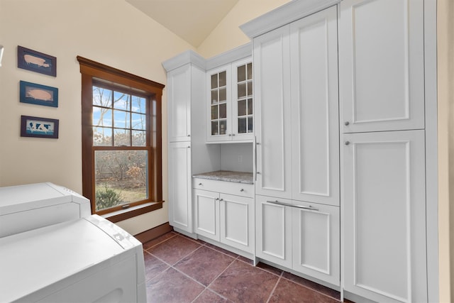 washroom with cabinets, washing machine and clothes dryer, dark tile patterned flooring, and a wealth of natural light