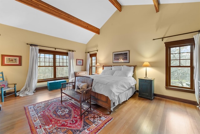 bedroom with light hardwood / wood-style floors, high vaulted ceiling, multiple windows, and beamed ceiling