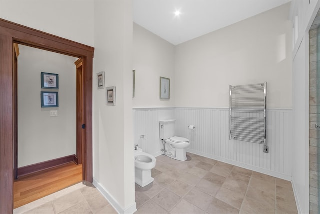 bathroom with radiator, toilet, tile patterned flooring, and a bidet