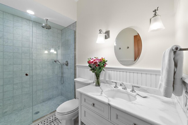 bathroom with tiled shower, vanity, and toilet