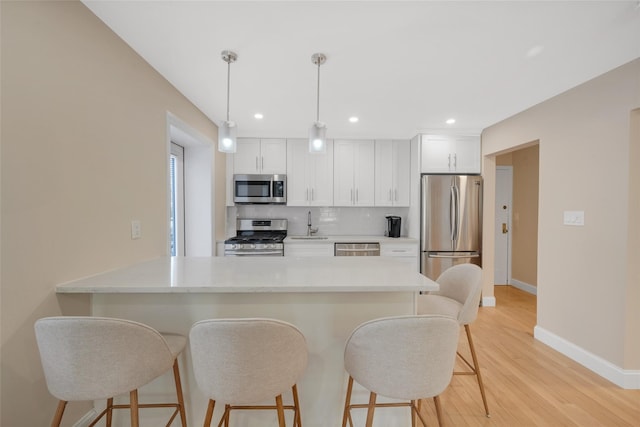 kitchen with sink, appliances with stainless steel finishes, pendant lighting, decorative backsplash, and white cabinets