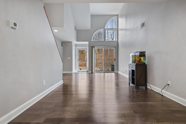 unfurnished living room with a high ceiling and dark hardwood / wood-style floors