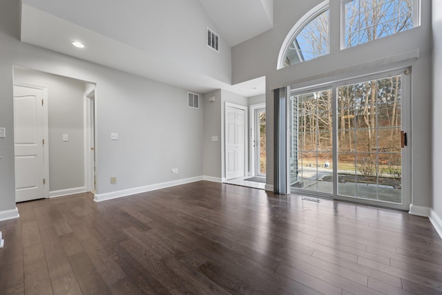 empty room featuring dark wood-type flooring and a towering ceiling