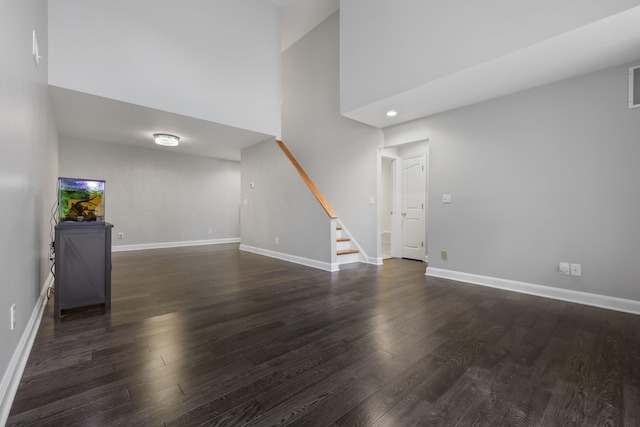 unfurnished living room with a high ceiling and dark hardwood / wood-style floors