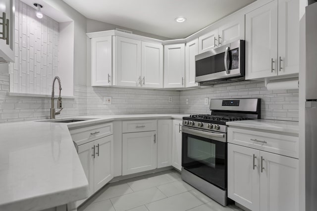 kitchen with white cabinets, appliances with stainless steel finishes, light tile patterned floors, and sink