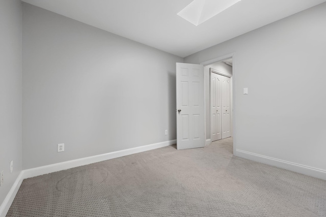 carpeted empty room featuring a skylight