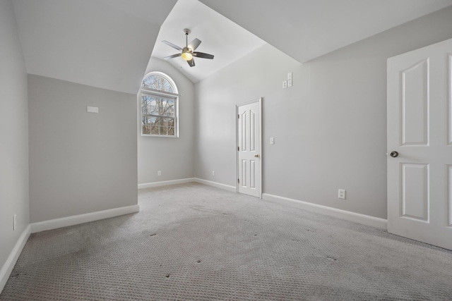 empty room with ceiling fan, vaulted ceiling, and light carpet