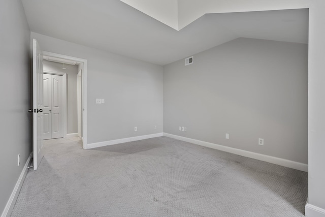 spare room featuring light colored carpet and lofted ceiling