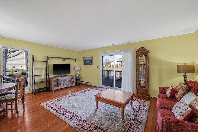 living room with a wealth of natural light, wood-type flooring, and a baseboard radiator