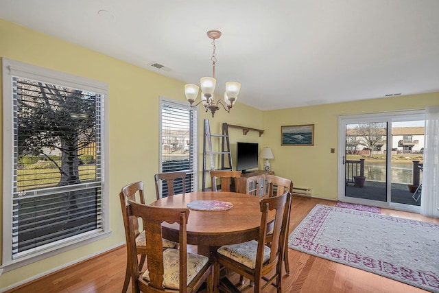 dining area with light wood-type flooring, baseboard heating, and a notable chandelier