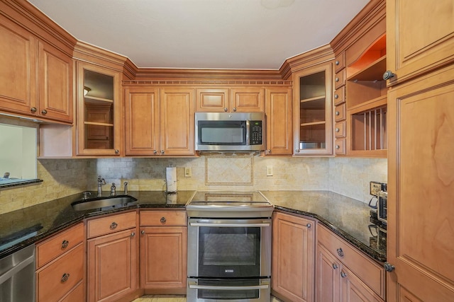 kitchen with stainless steel appliances, dark stone countertops, tasteful backsplash, and sink