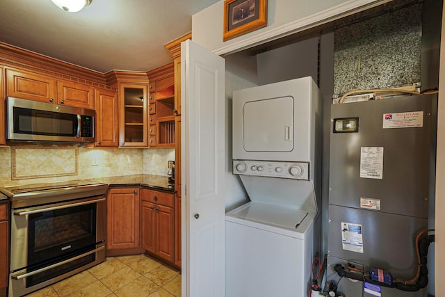 kitchen with stacked washer and dryer, light tile patterned floors, stainless steel appliances, backsplash, and stone counters