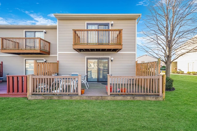 back of house featuring a lawn, a balcony, and a wooden deck