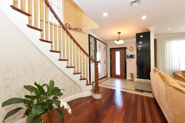 foyer entrance with crown molding, a wealth of natural light, and dark hardwood / wood-style floors