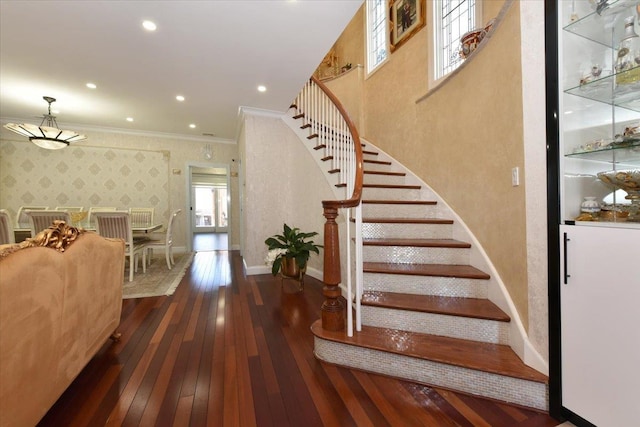 staircase with ornamental molding and hardwood / wood-style floors