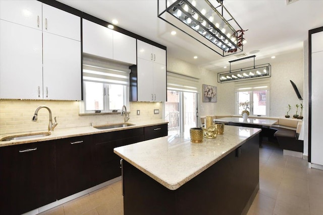 kitchen with white cabinetry, sink, hanging light fixtures, and a kitchen island