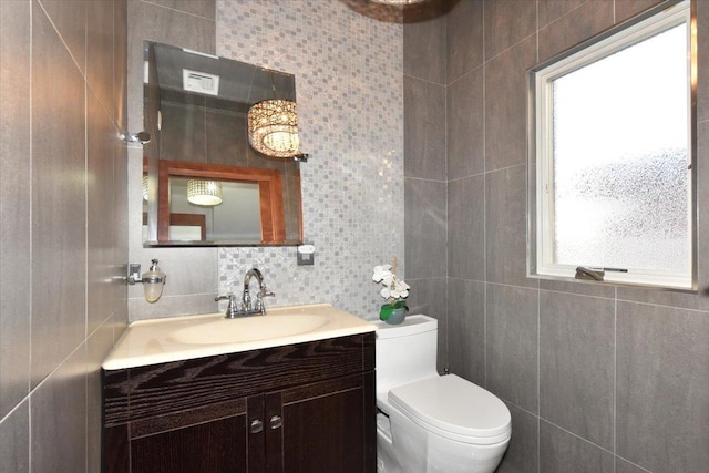 bathroom featuring vanity, toilet, tile walls, and decorative backsplash