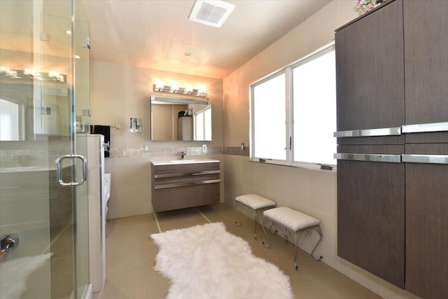 bathroom featuring tile patterned flooring, vanity, tile walls, and walk in shower