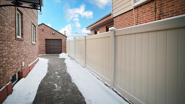 snow covered property with a garage and an outbuilding