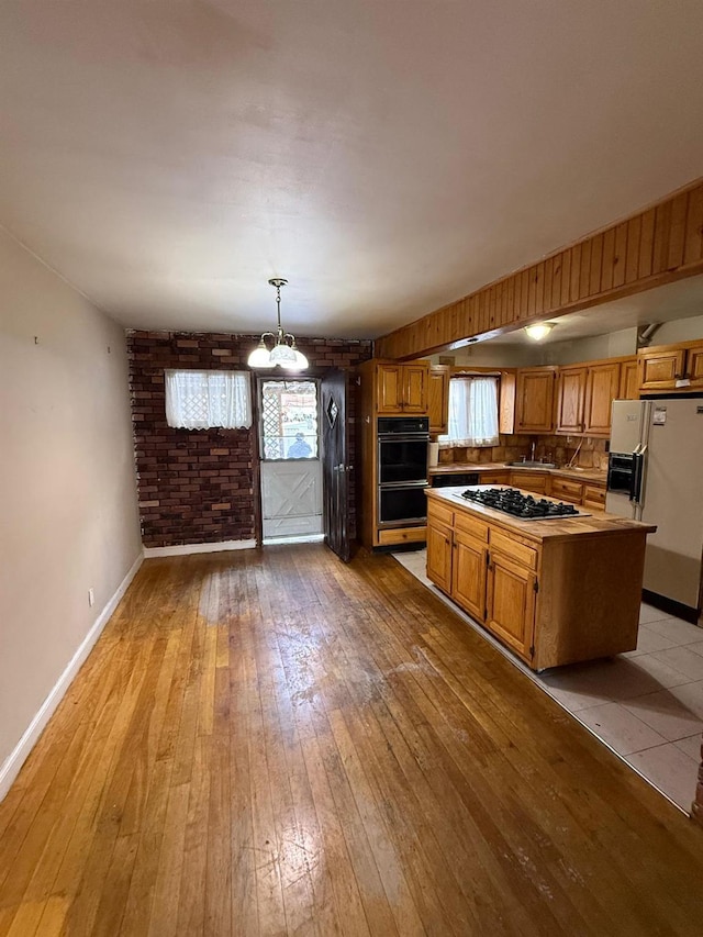 kitchen featuring a center island, black appliances, sink, light hardwood / wood-style flooring, and hanging light fixtures