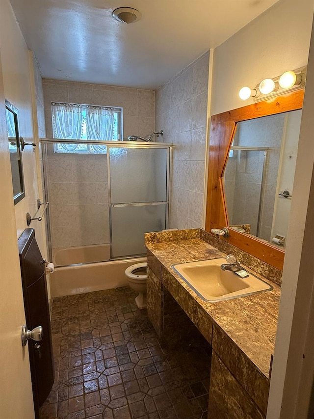 full bathroom featuring toilet, shower / bath combination with glass door, and sink