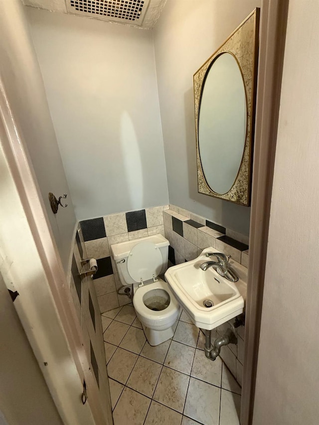 bathroom with toilet, tile walls, sink, and tile patterned flooring