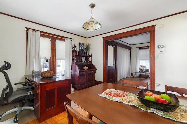 dining space with light wood-type flooring, crown molding, and a healthy amount of sunlight