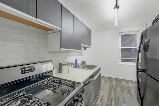 kitchen featuring sink, backsplash, dishwashing machine, black refrigerator, and stainless steel range with gas stovetop