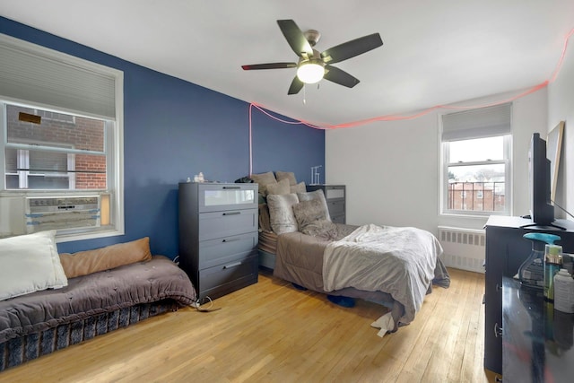 bedroom with ceiling fan, radiator heating unit, and light hardwood / wood-style flooring