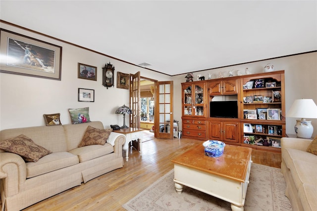 living room featuring french doors, ornamental molding, and light hardwood / wood-style floors