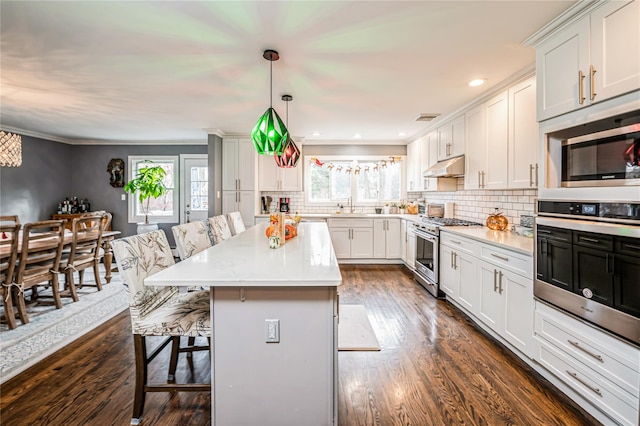 kitchen featuring stainless steel appliances, hanging light fixtures, a breakfast bar, a kitchen island, and white cabinets