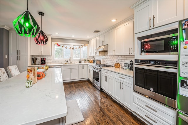 kitchen featuring appliances with stainless steel finishes, hanging light fixtures, light stone countertops, white cabinets, and sink