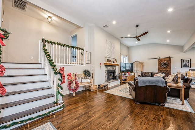 living room with ceiling fan, dark wood-type flooring, a barn door, and lofted ceiling