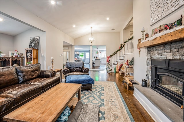 living room with vaulted ceiling, dark hardwood / wood-style flooring, and a stone fireplace