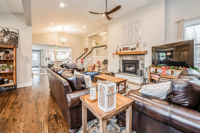 living room featuring dark hardwood / wood-style flooring, vaulted ceiling, ceiling fan with notable chandelier, and a fireplace