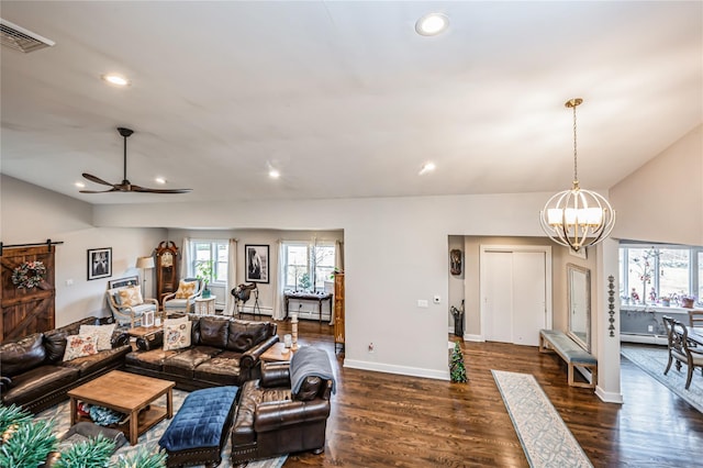 living room featuring ceiling fan with notable chandelier, lofted ceiling, a barn door, and dark hardwood / wood-style floors