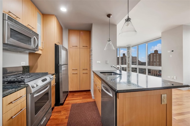 kitchen featuring pendant lighting, sink, light wood-type flooring, stainless steel appliances, and light brown cabinetry