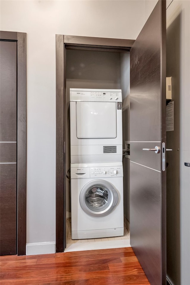 clothes washing area featuring stacked washing maching and dryer and hardwood / wood-style flooring