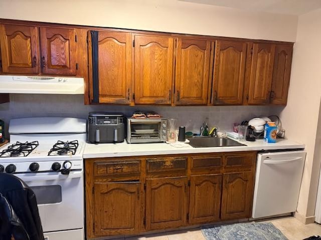 kitchen with white appliances, sink, and light tile patterned floors