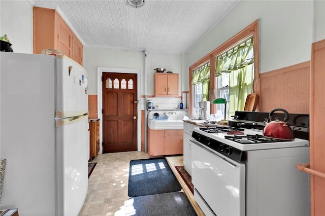 kitchen featuring white appliances, sink, and light brown cabinetry