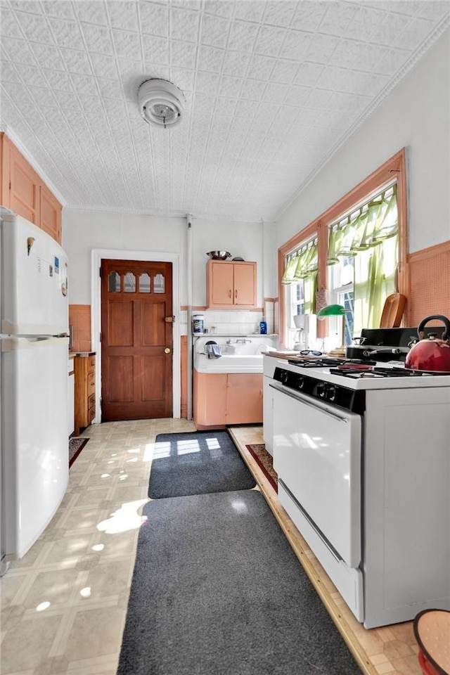 kitchen featuring backsplash, light brown cabinetry, and white appliances