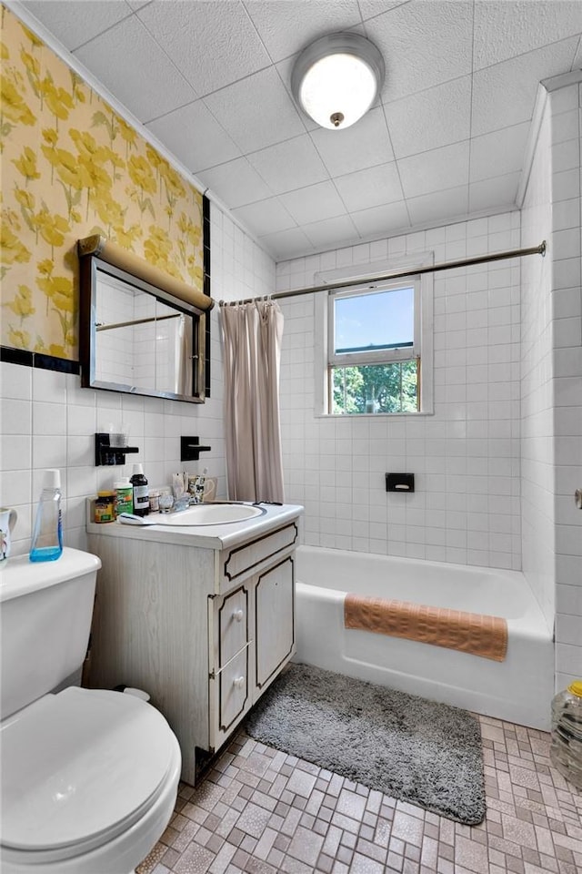 full bathroom featuring shower / bath combo, toilet, tile walls, and vanity