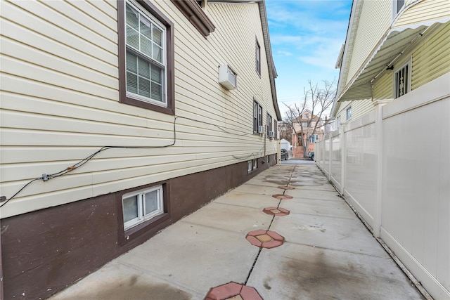 view of property exterior with a patio and a wall mounted AC