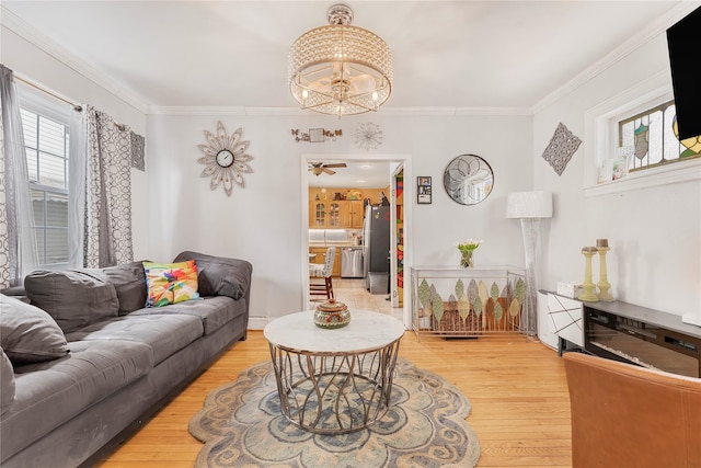 living room featuring hardwood / wood-style floors, ceiling fan with notable chandelier, and ornamental molding