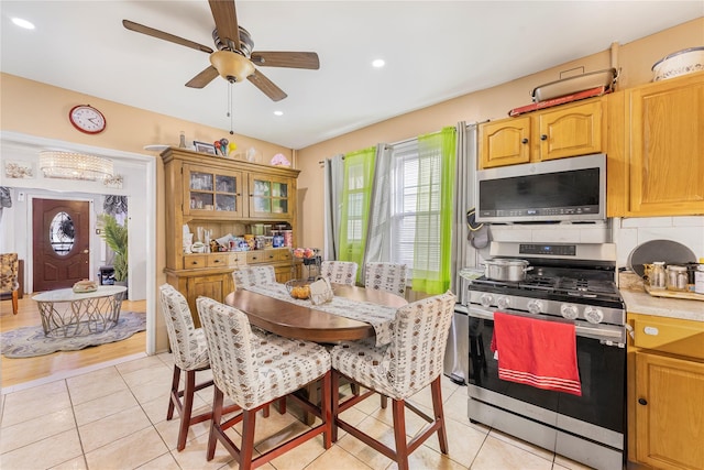 kitchen featuring backsplash, ceiling fan, light tile patterned flooring, and stainless steel appliances